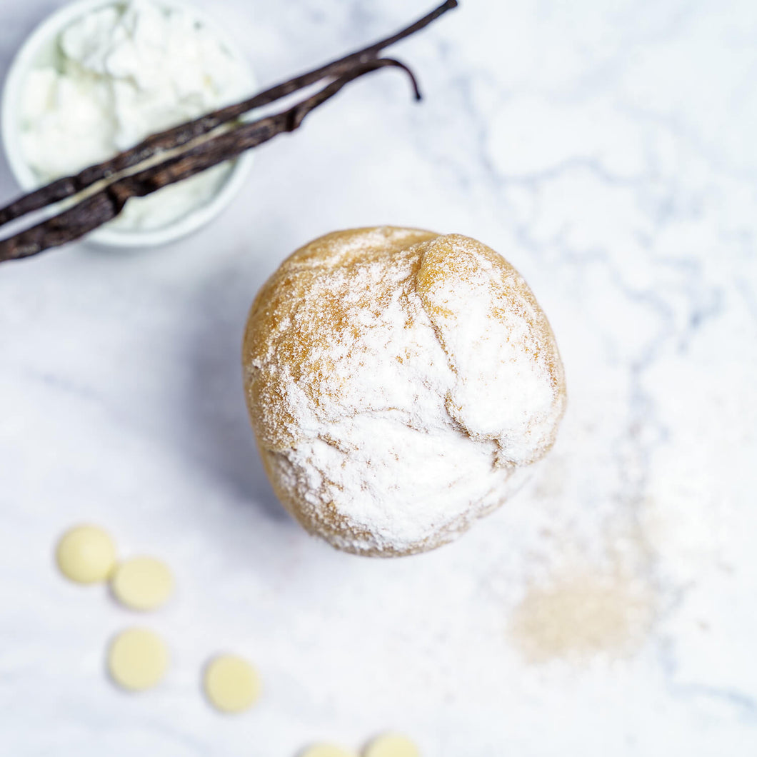 Windbeutel, mit Vanillecreme und mit Puderzucker bestreut von oben, zur Deko eine Vanilleschote und weiße Schokostückchen