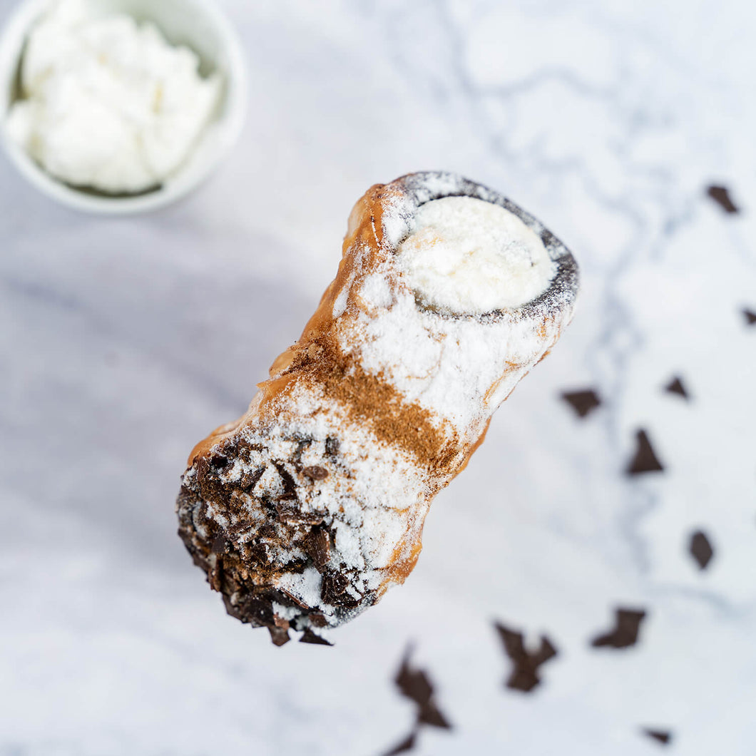 von oben Ricotta Cannolo – Frittierte Mürbteigröllchen, innen mit Schokolade ausgestrichen, gefüllt mit Ricottacreme und Puderzucker bestreut